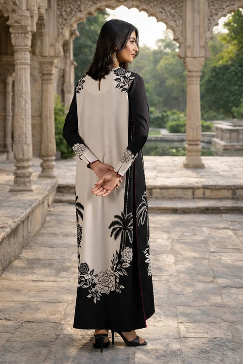 Woman in a black and white dress with floral patterns standing in an outdoor setting with architectural elements.