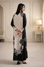 Woman wearing a black and white embroidered dress in an elegant room.