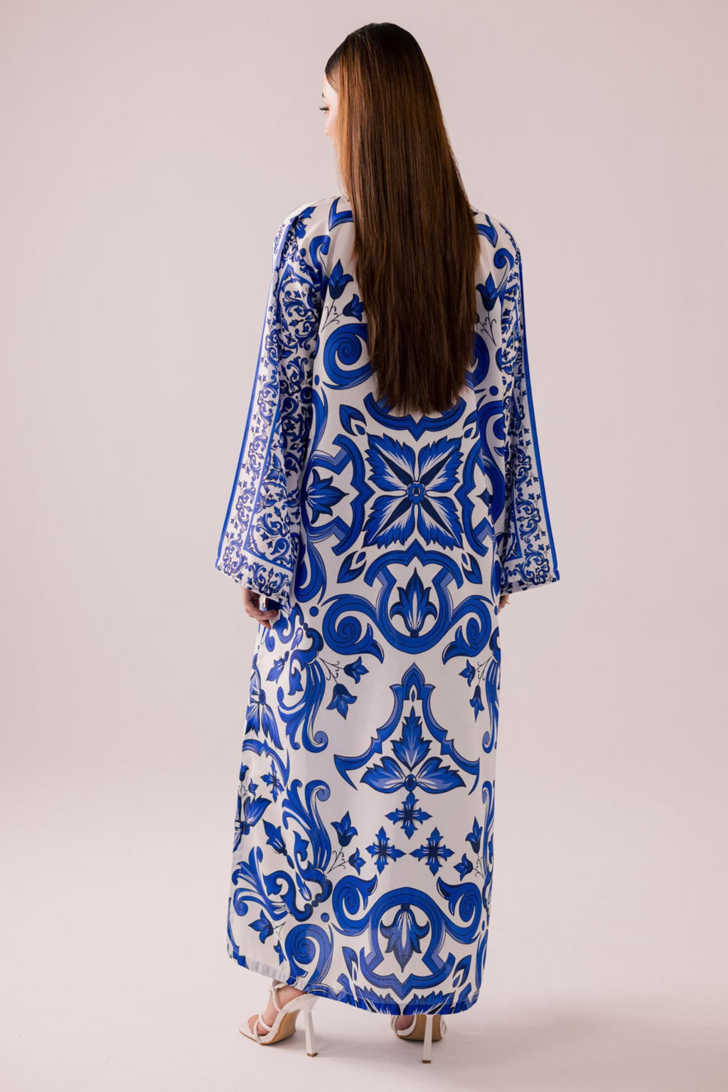 Woman wearing a blue and white patterned dress on a plain background