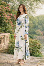 Woman wearing a floral dress standing outdoors with greenery in the background