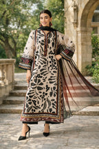Woman in a patterned dress standing outdoors with trees and architecture in the background