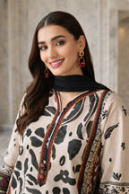 Woman wearing a patterned outfit with a black scarf and earrings against a neutral background