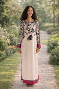 Woman in a long, elegant dress with floral patterns standing on a garden path.