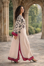 Woman in a traditional outfit with floral patterns standing in an outdoor setting.